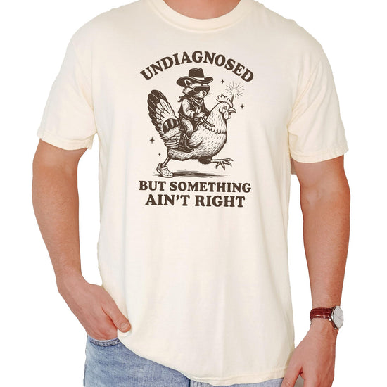 Product flat lay of blue jean colored shirt with raccoon humor graphic design