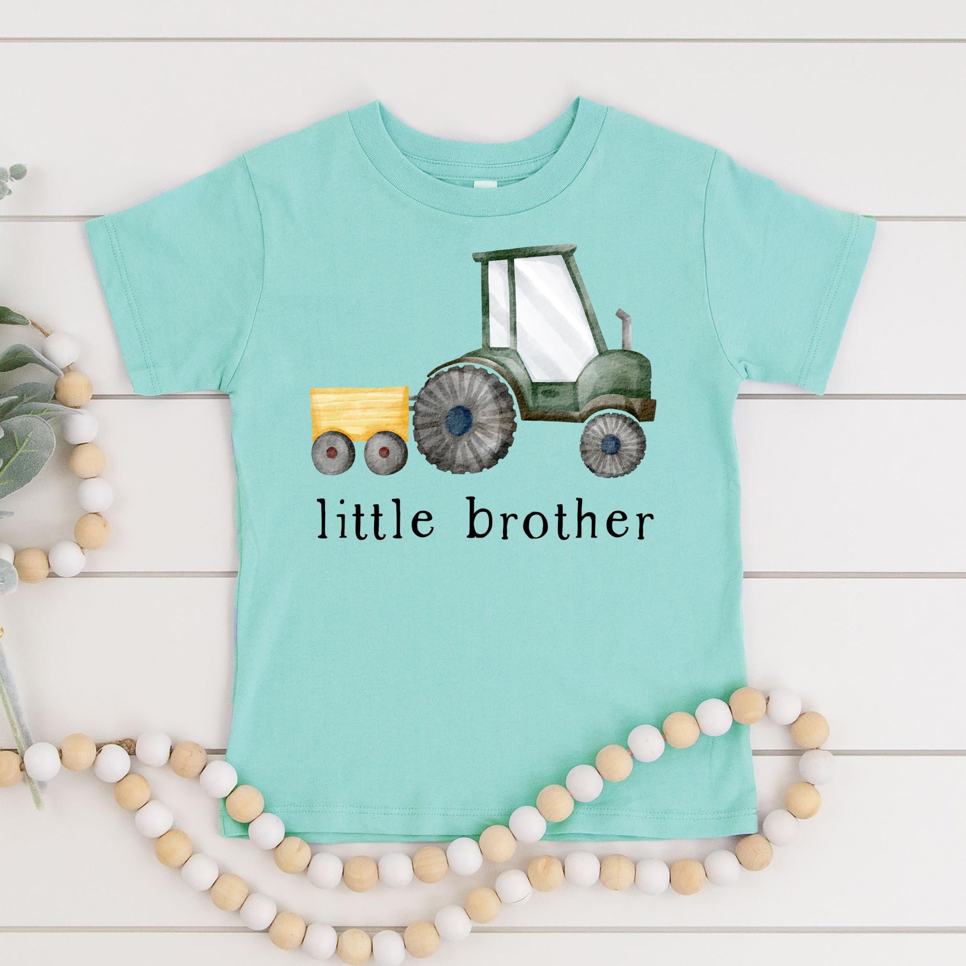 Detail shot of little brother tractor graphic print quality on natural bodysuit fabric
