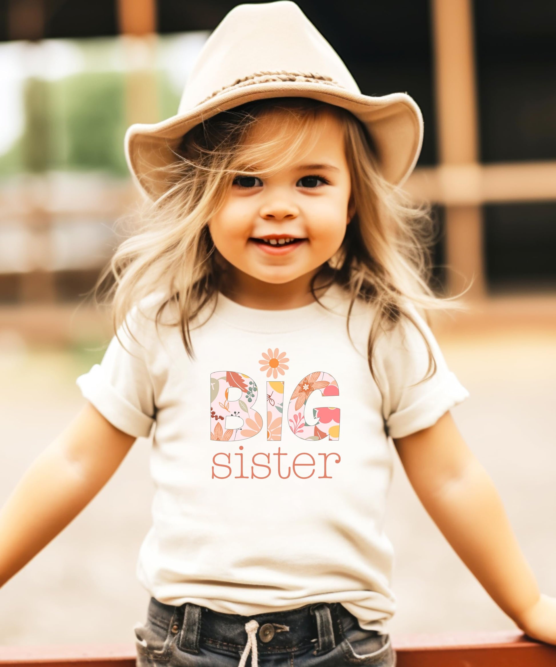 Toddler girl in a girly floral Big Sister shirt with daisy graphic in soft colors