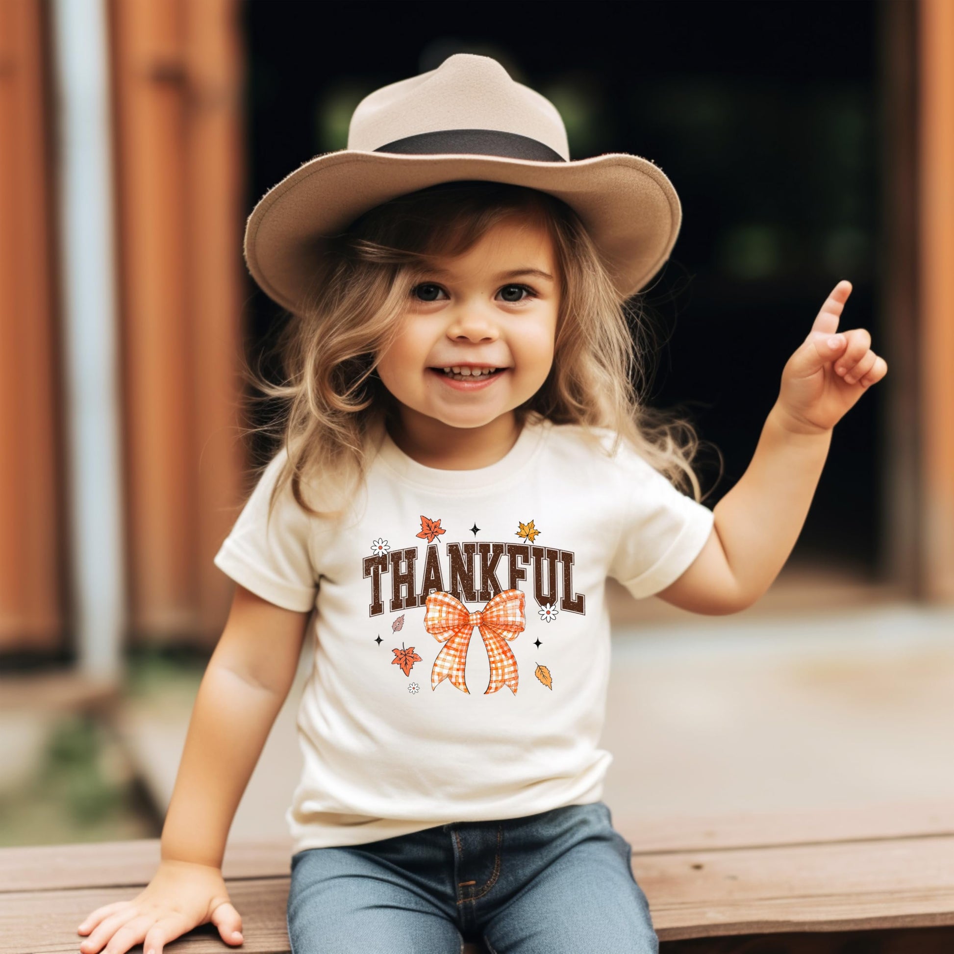 Thanksgiving tee for girls and toddlers featuring orange thankful text with bow accent
