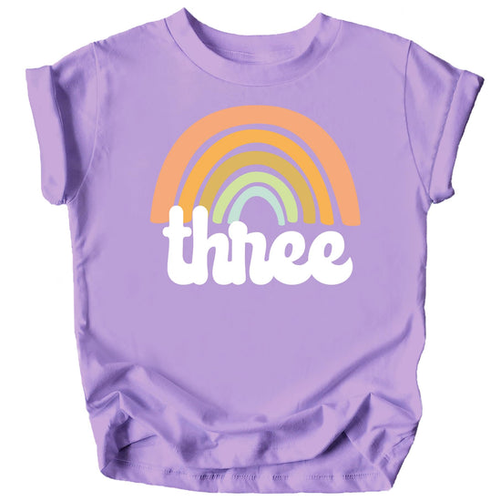 Toddler girl wearing a retro rainbow third birthday shirt in purple with bold graphic print