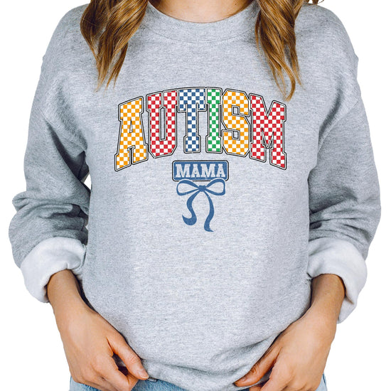 Close-up of bold multicolor checkered Autism Mama print on white sweatshirt