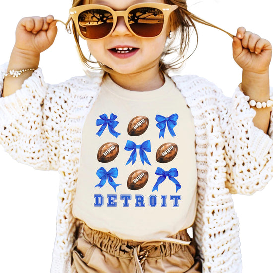 Model wearing Detroit football coquette bow tee in natural color, casual game day style