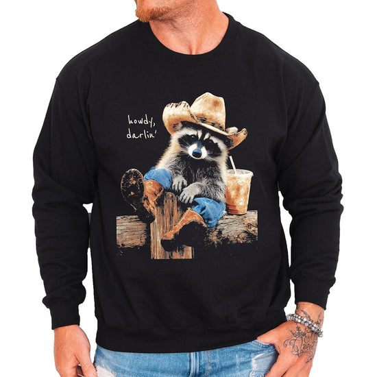 Flat lay of black crewneck sweatshirt with funny western raccoon design on the chest