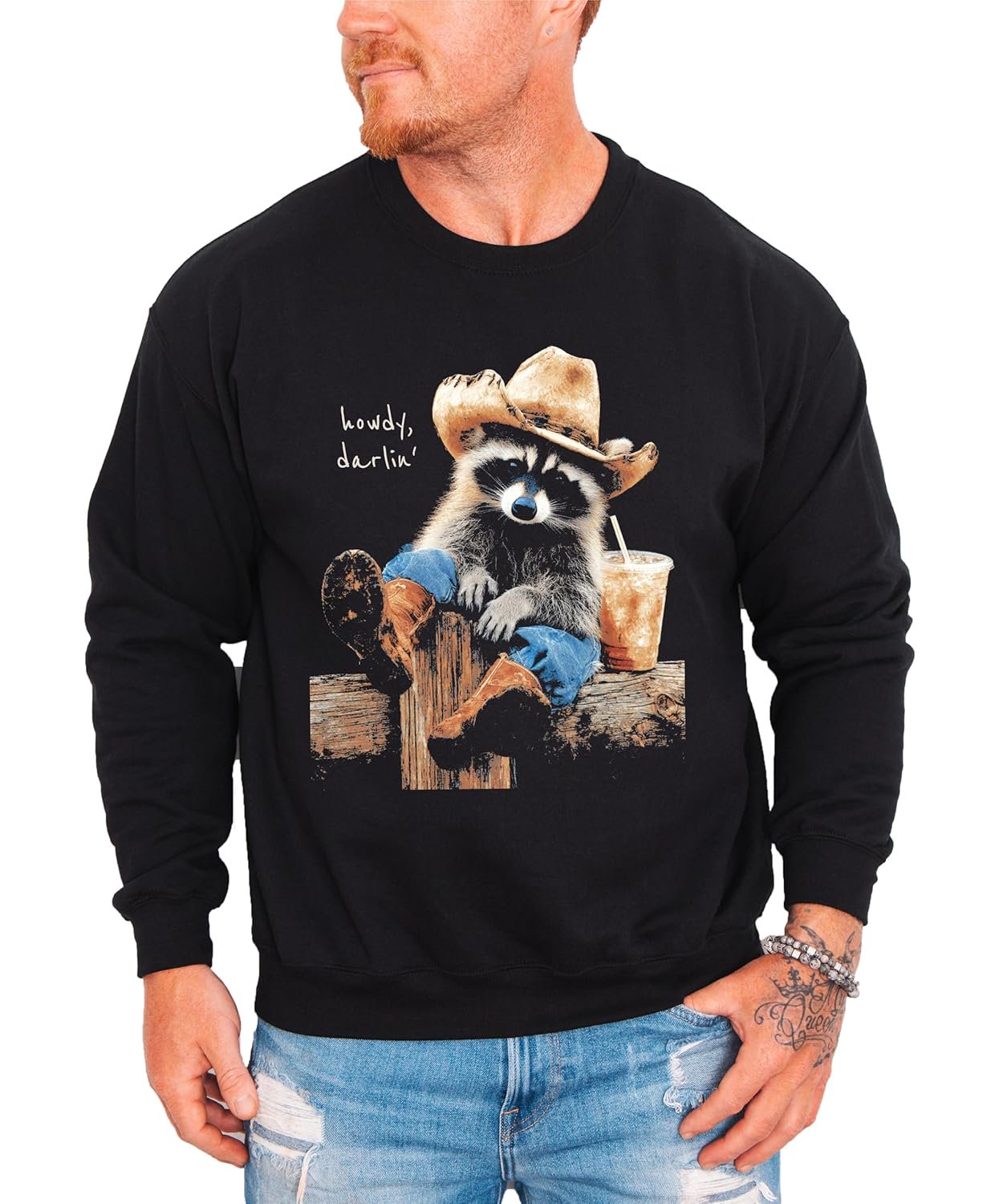 Flat lay of black crewneck sweatshirt with funny western raccoon design on the chest