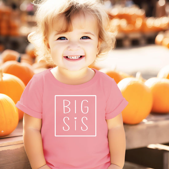 Flat lay of purple Big Sis graphic tee for baby and toddler girls sibling reveal outfit