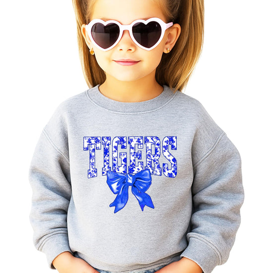 Close-up of Tigers blue floral print text with decorative bow graphic on sweatshirt