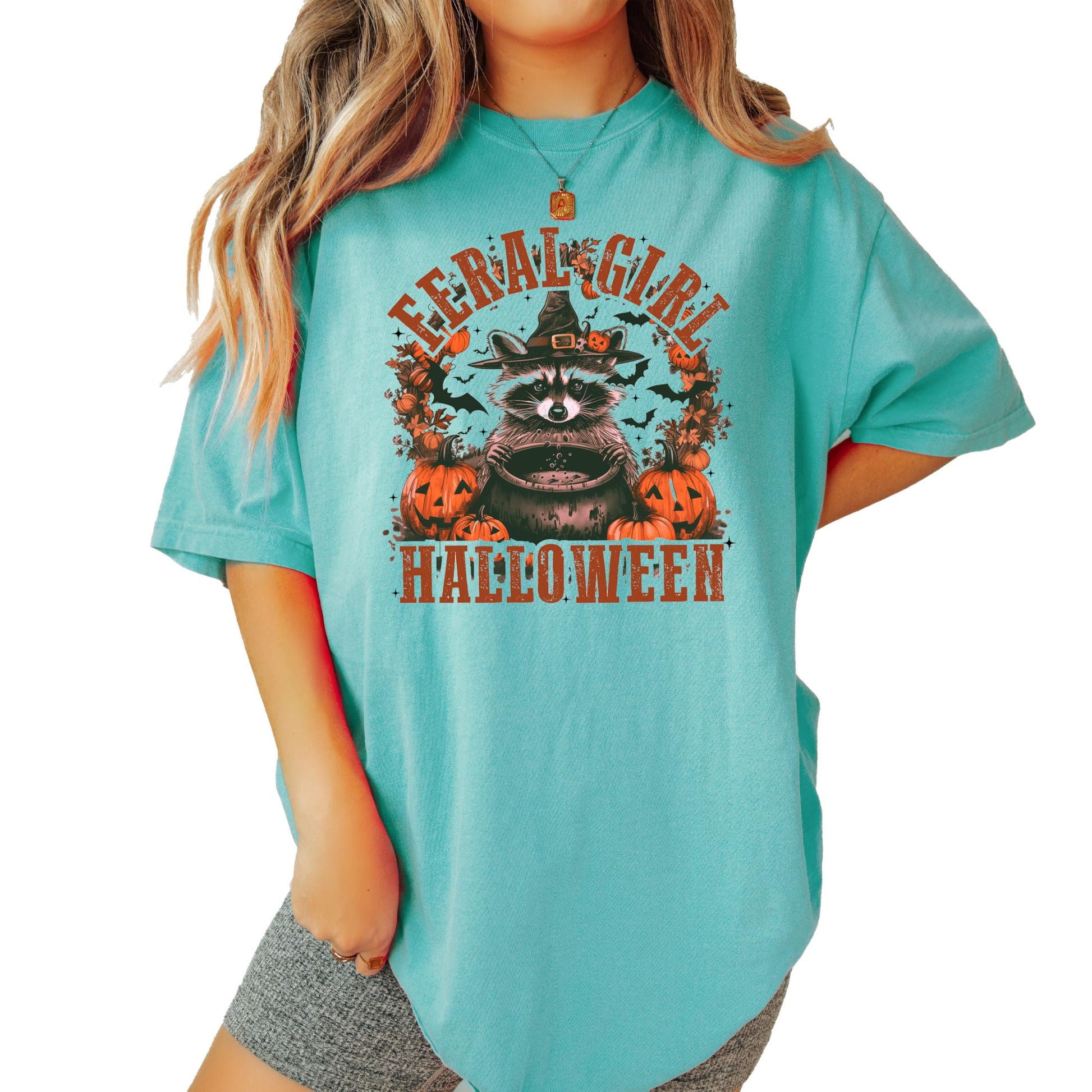 Front view of the Feral Girl Halloween graphic tee in seafoam with raccoon witch hat design
