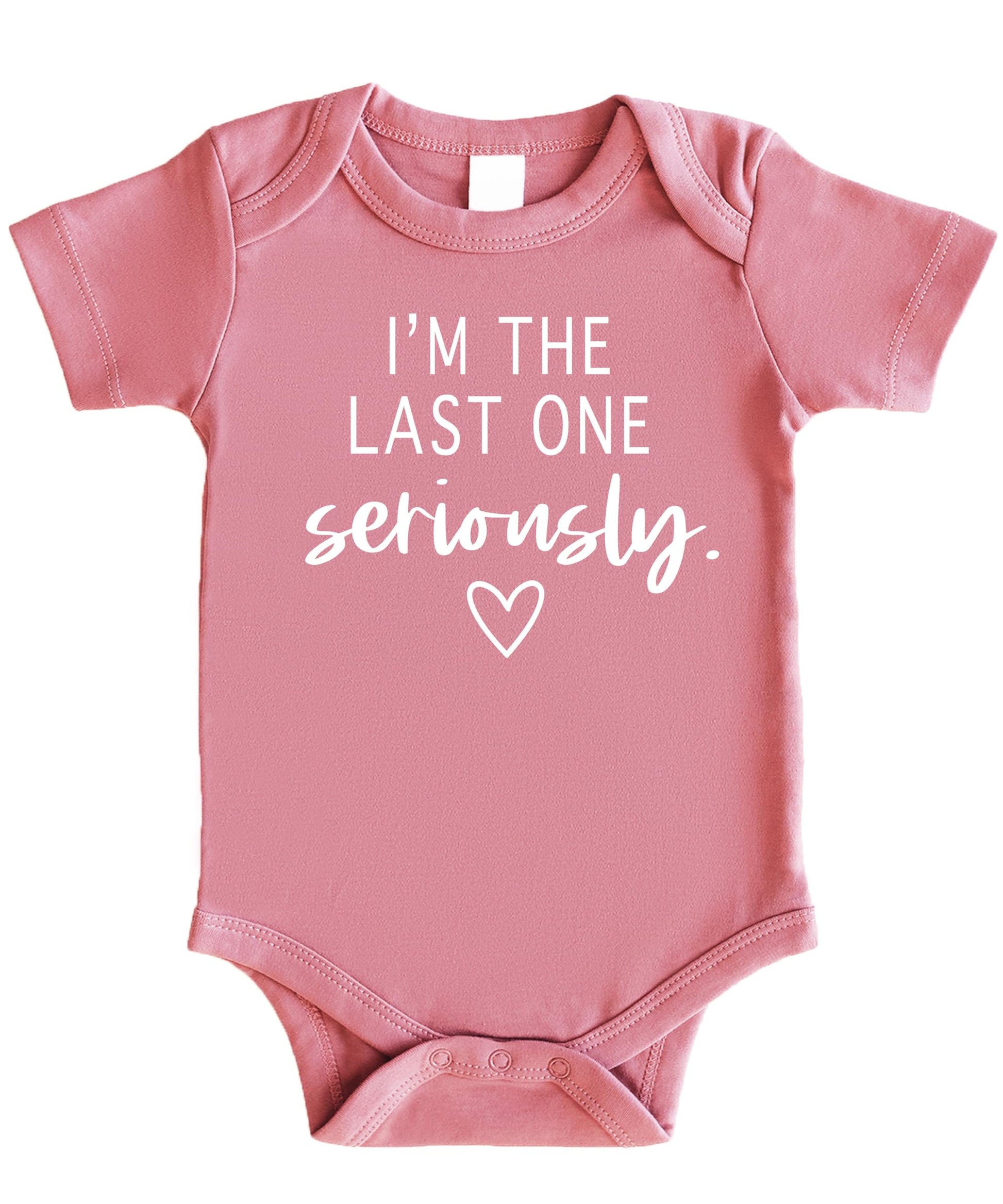 Flat lay of funny last baby bodysuit in white on mauve styling for newborn coming home outfit