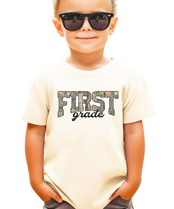 Flat lay of First Grade camouflage shirt in military green — kids unisex back to school tee
