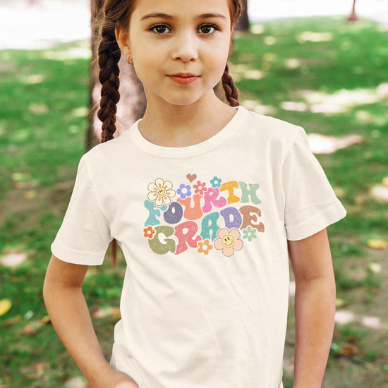 Flat lay of 4th grade groovy daisy first day of school t-shirt