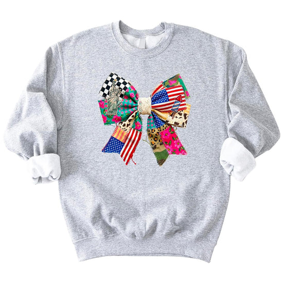 Close-up of coquette ribbon bow graphic on white sweatshirt with American flag, florals, and checkered patriotic print details