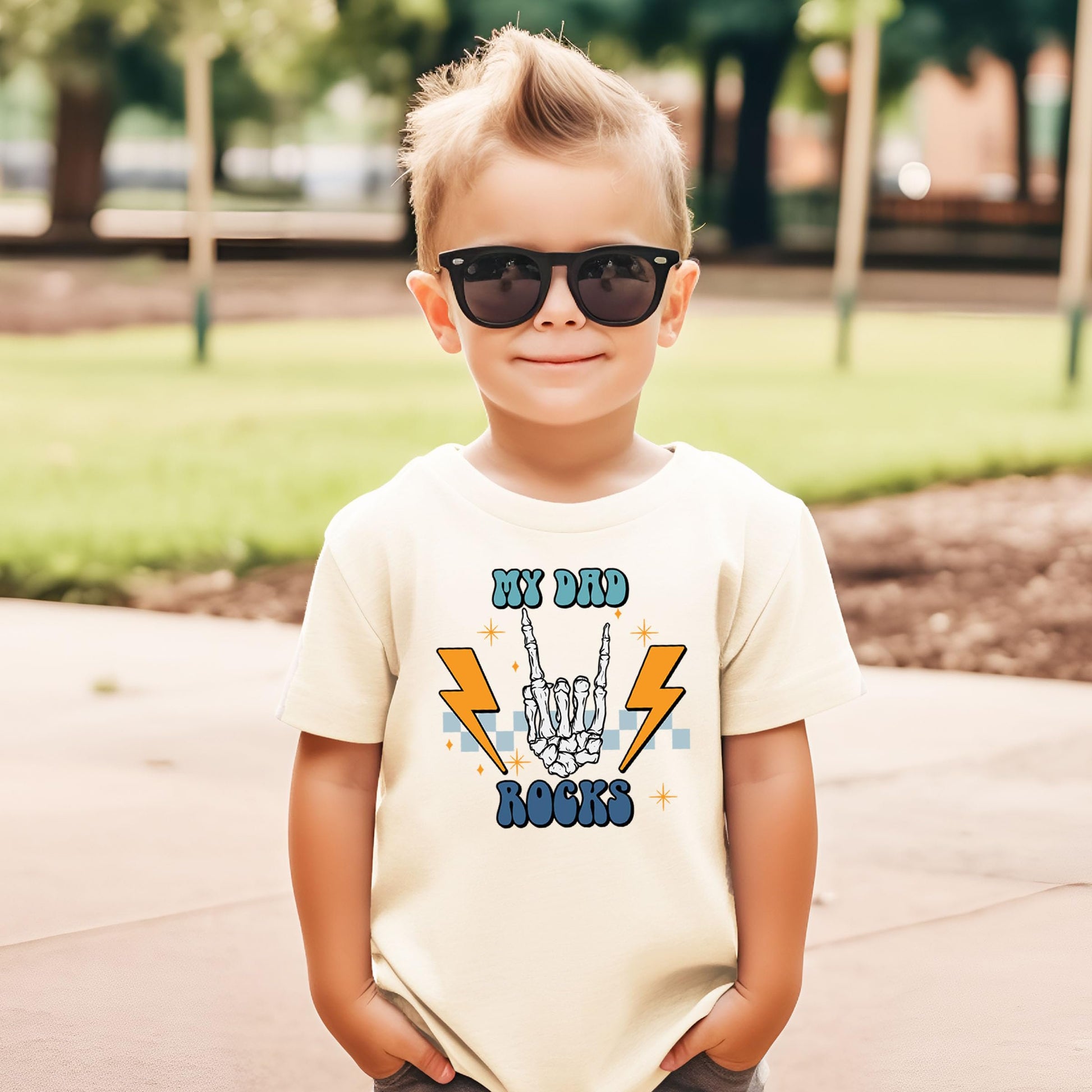 Front view of My Dad Rocks retro rocker skeleton hand kids t-shirt in natural
