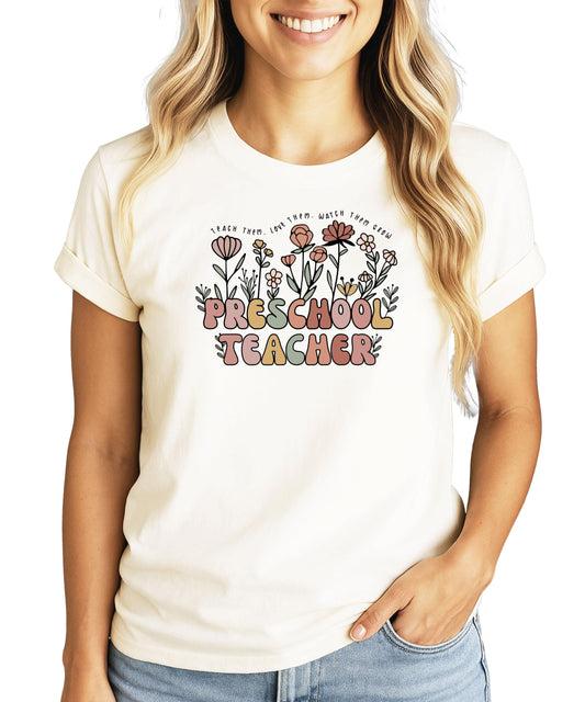 Close-up view of floral teach them love them watch them grow graphic design on peach teacher shirt