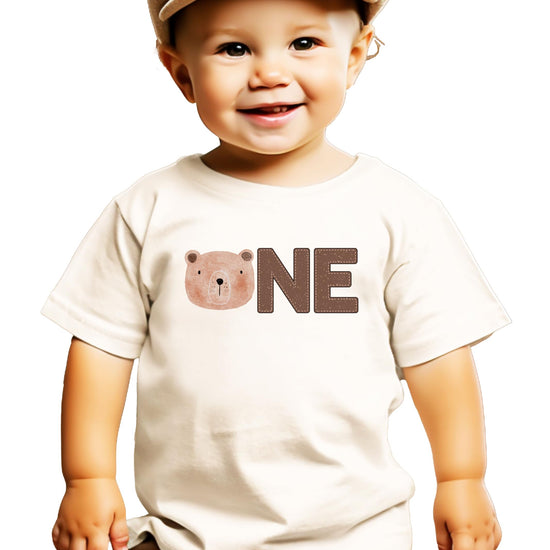 Close-up of bear-themed ONE graphic on a natural boys first birthday shirt