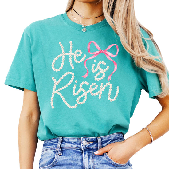 Women modeling He Is Risen faith graphic tee — perfect Easter church outfit with pink bow detail