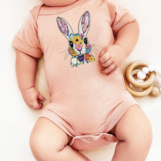 Detail shot of embroidery-style bunny and floral print on infant snap bodysuit