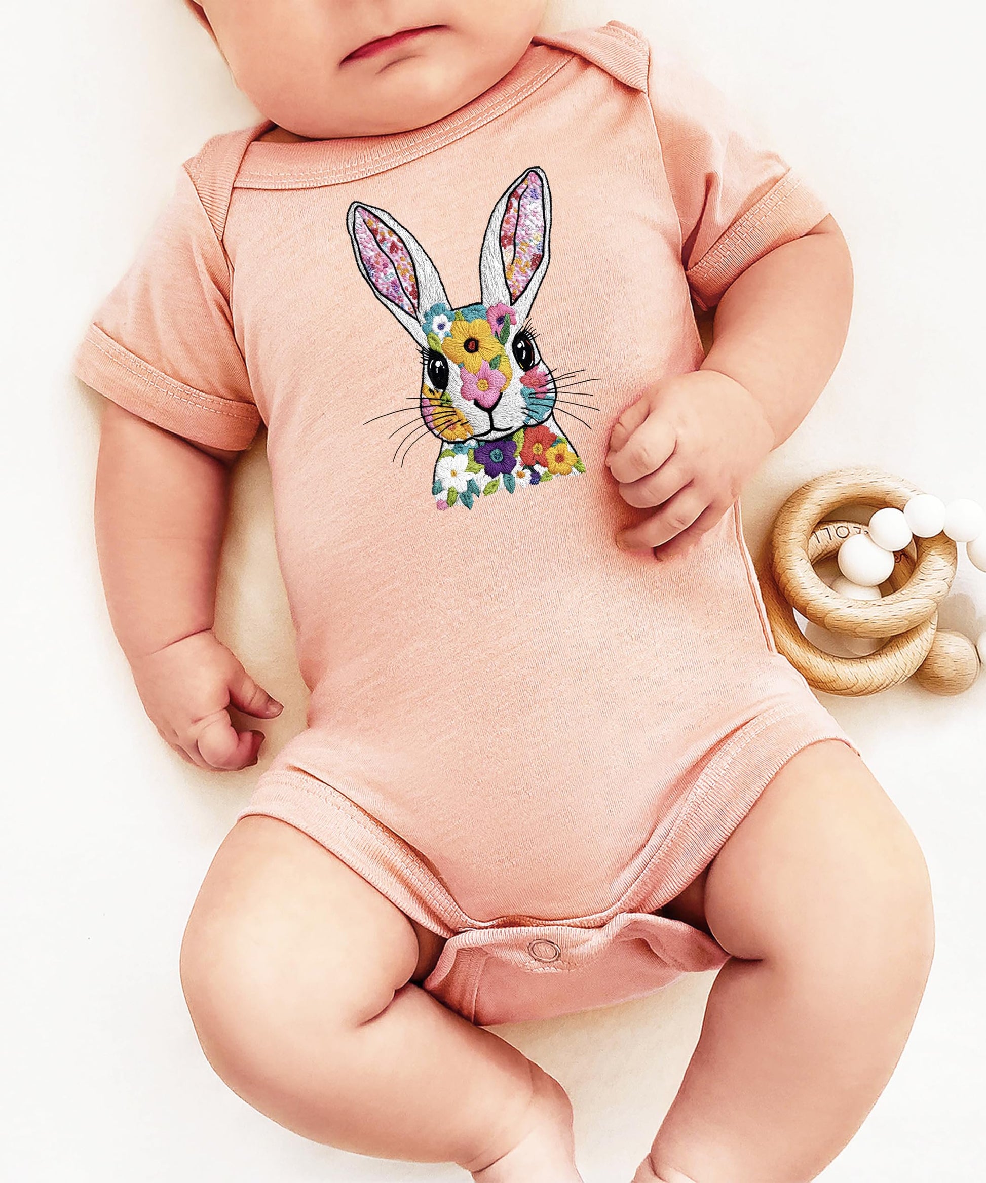 Detail shot of embroidery-style bunny and floral print on infant snap bodysuit