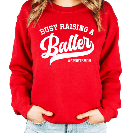 Front view of Busy Raising a Baller black sweatshirt for women, cozy fleece sports mom style