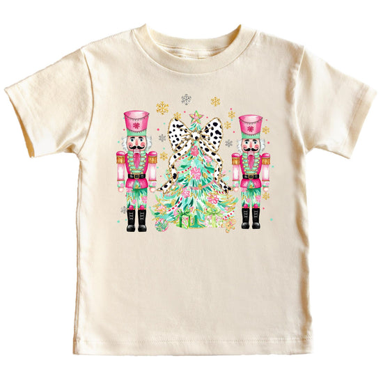Close-up of vibrant nutcracker and Christmas tree print on a soft peach holiday shirt