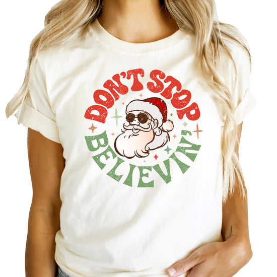 Front view of festive Don't Stop Believing Santa holiday shirt for women