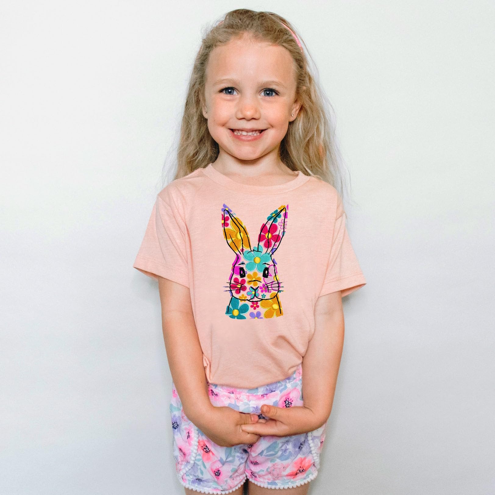 Close-up of vibrant floral Easter bunny design on peach girls graphic tee