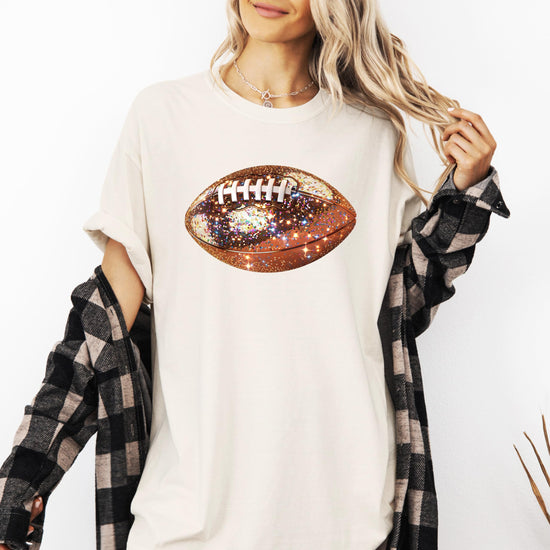 Woman wearing oversized glitter football graphic tee styled casually for game day