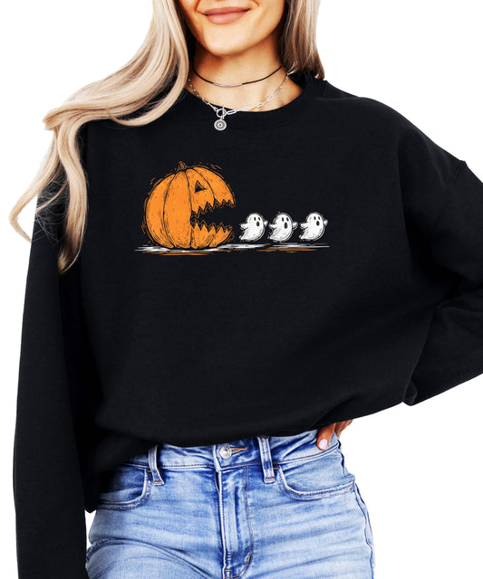 Women wearing a cozy Halloween sweatshirt with a carved pumpkin chomping ghosts graphic
