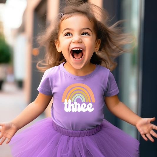 Little girl in a retro rainbow 3rd birthday outfit shirt, perfect for birthday party photos