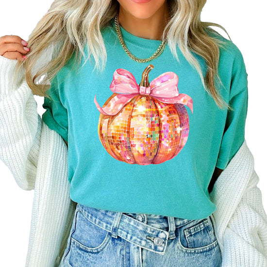 Close-up of disco ball pumpkin with pink bow graphic printed on seafoam green women's t-shirt