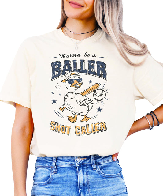 Ivory baseball shirt with "Wanna Be A Baller Shot Caller" text and cartoon duck graphic design