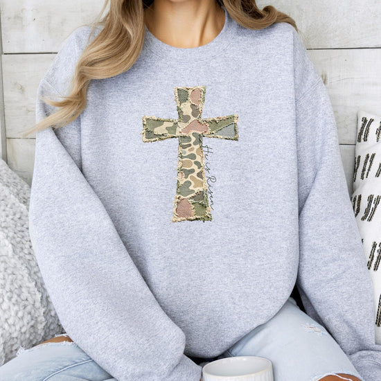 Detail shot of He Is Risen cross design on women's army green camo graphic sweatshirt