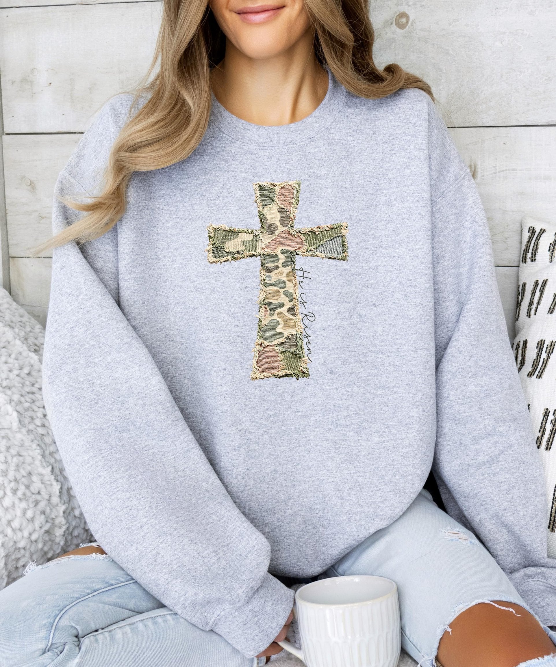 Detail shot of He Is Risen cross design on women's army green camo graphic sweatshirt