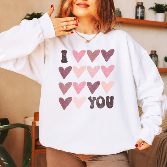 Lifestyle flat lay of Olive Loves Apple Galentine's Day sweatshirt featuring I Love You graphic design