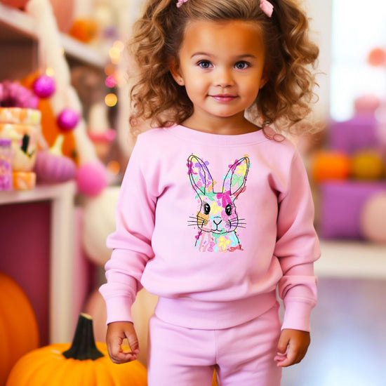 Young girl wearing white Easter Bunny coquette bows sweatshirt in spring setting
