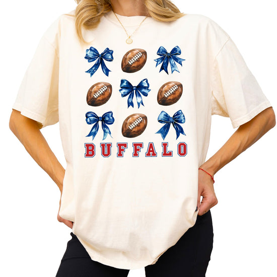Front view of ivory girly Buffalo football graphic tee with bows and football design for women