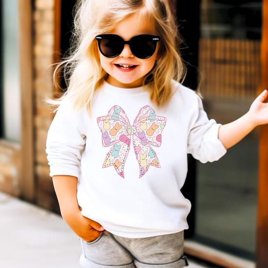 Flat lay of girls Easter sweatshirt featuring pastel bows, bunnies, and spring flowers