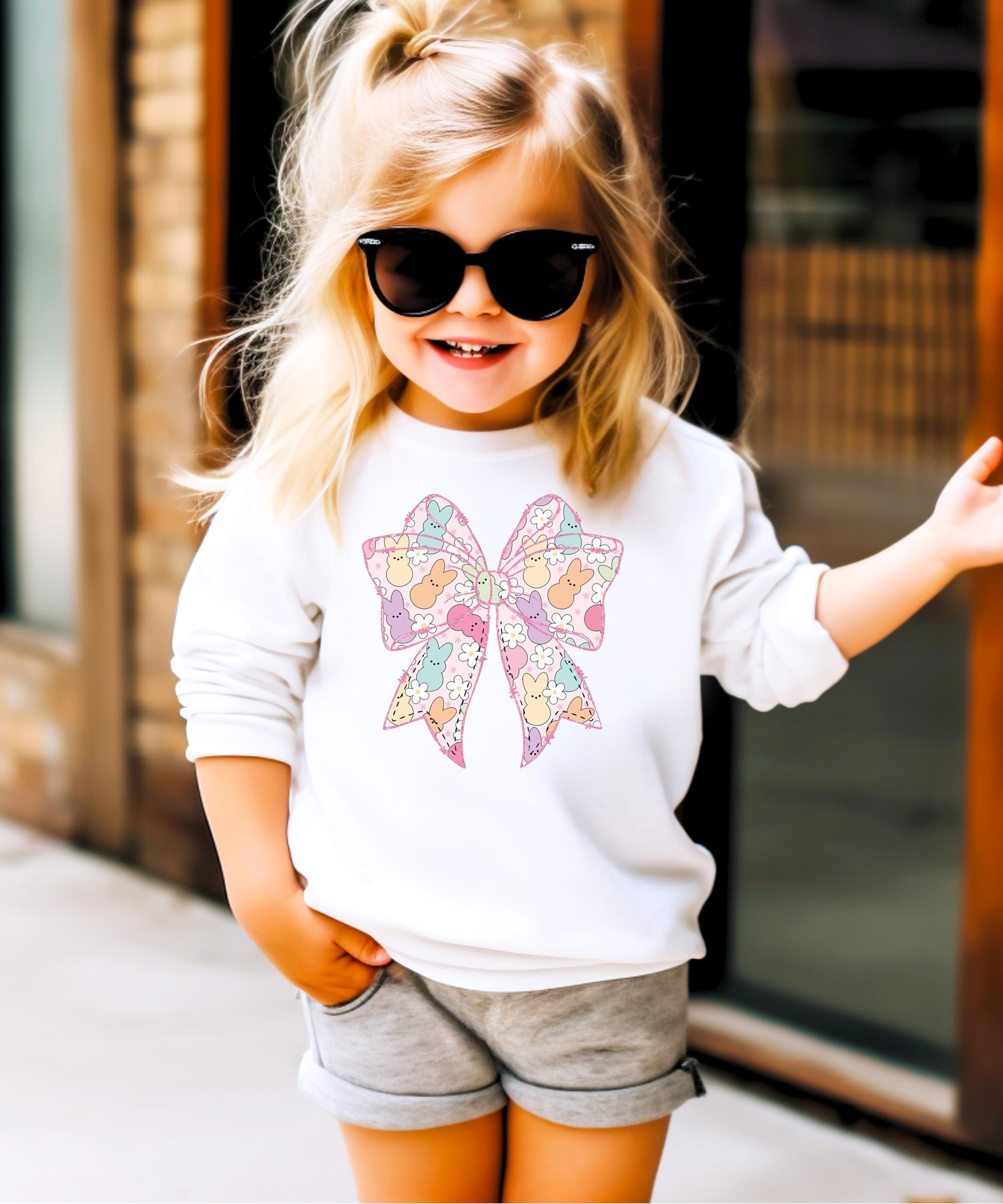 Flat lay of girls Easter sweatshirt featuring pastel bows, bunnies, and spring flowers