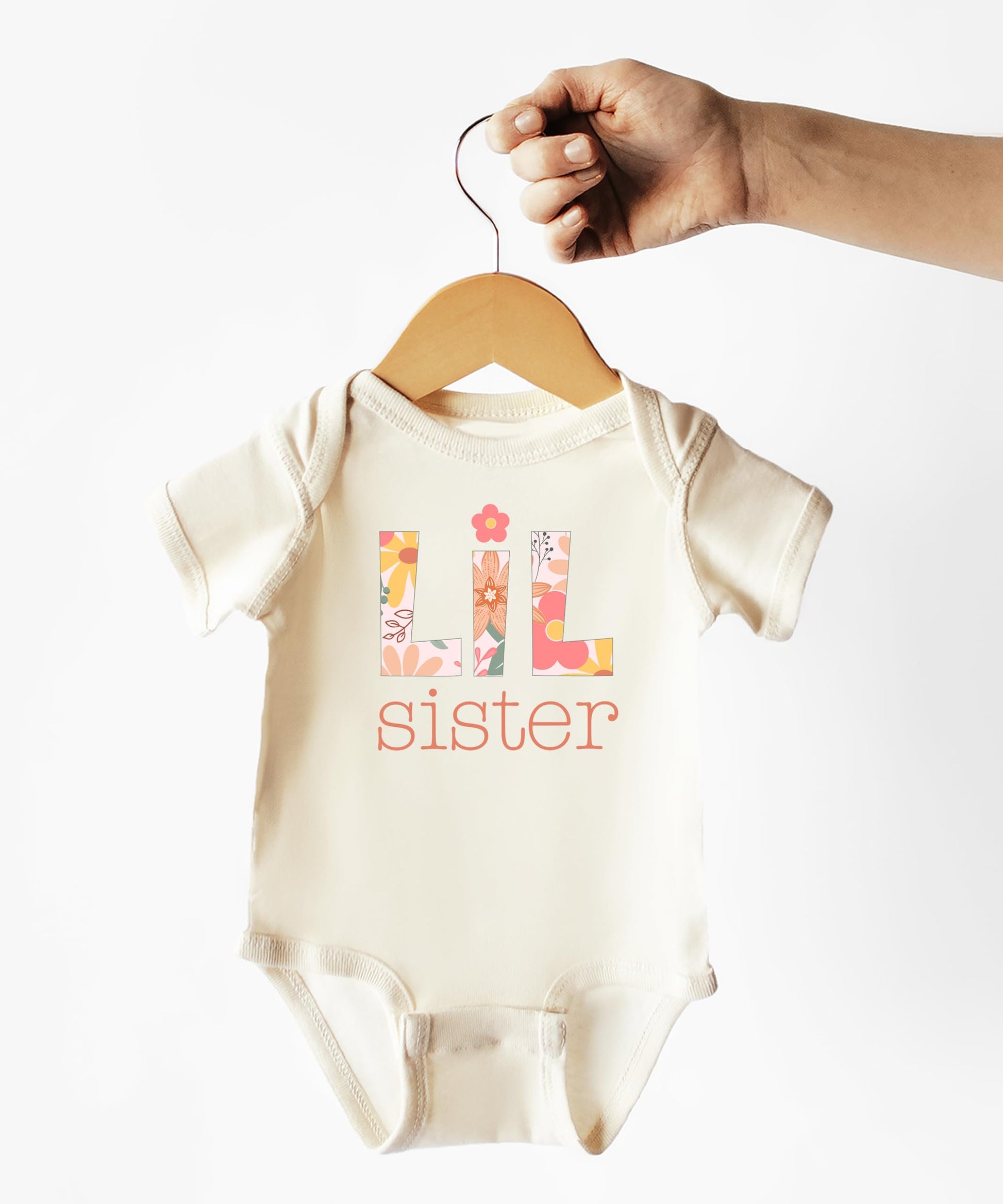 Flat lay of Lil Sister floral baby bodysuit in peach, newborn to 24 months