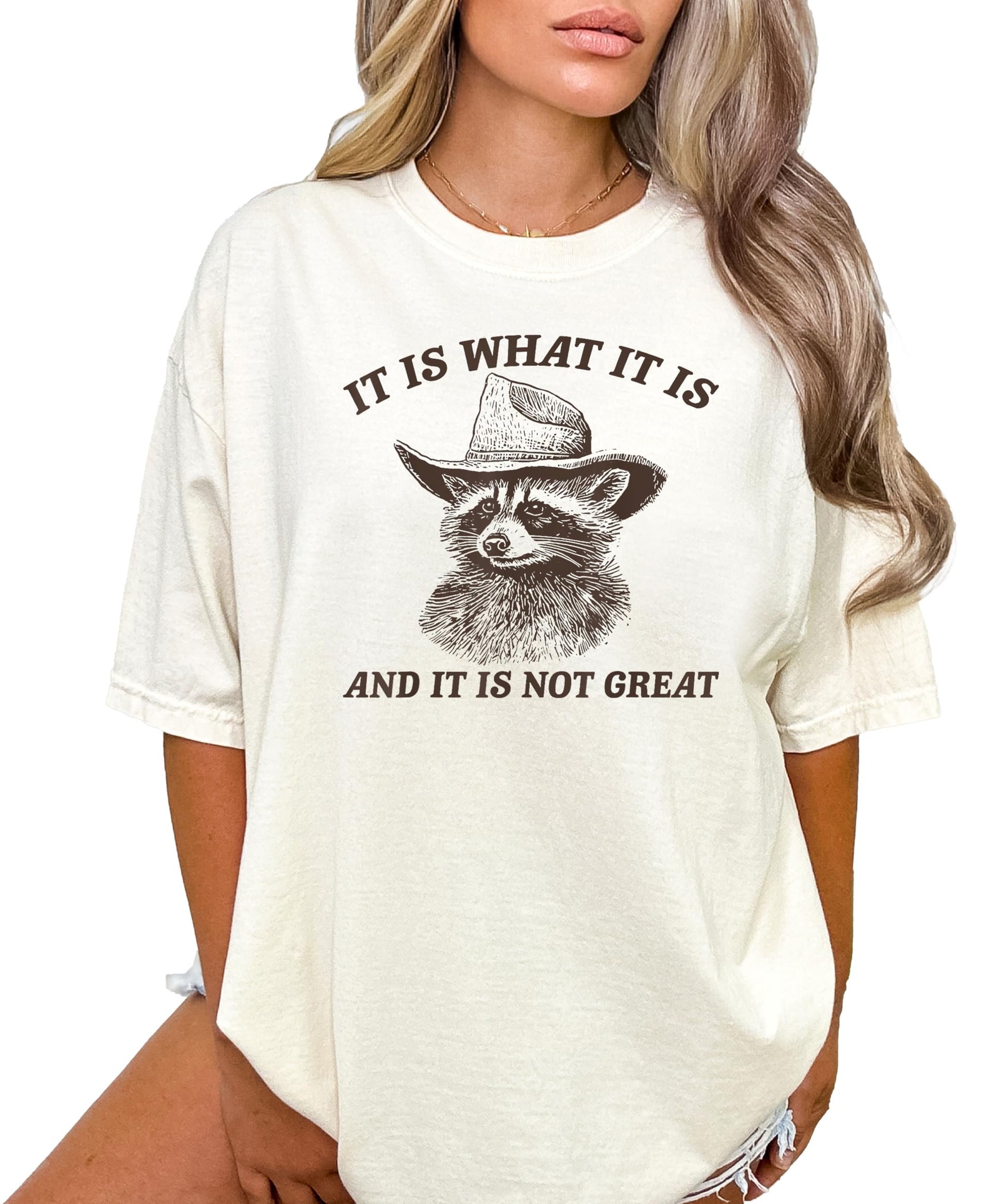 Close-up of the cowboy raccoon graphic and humorous slogan on an ivory women's tee