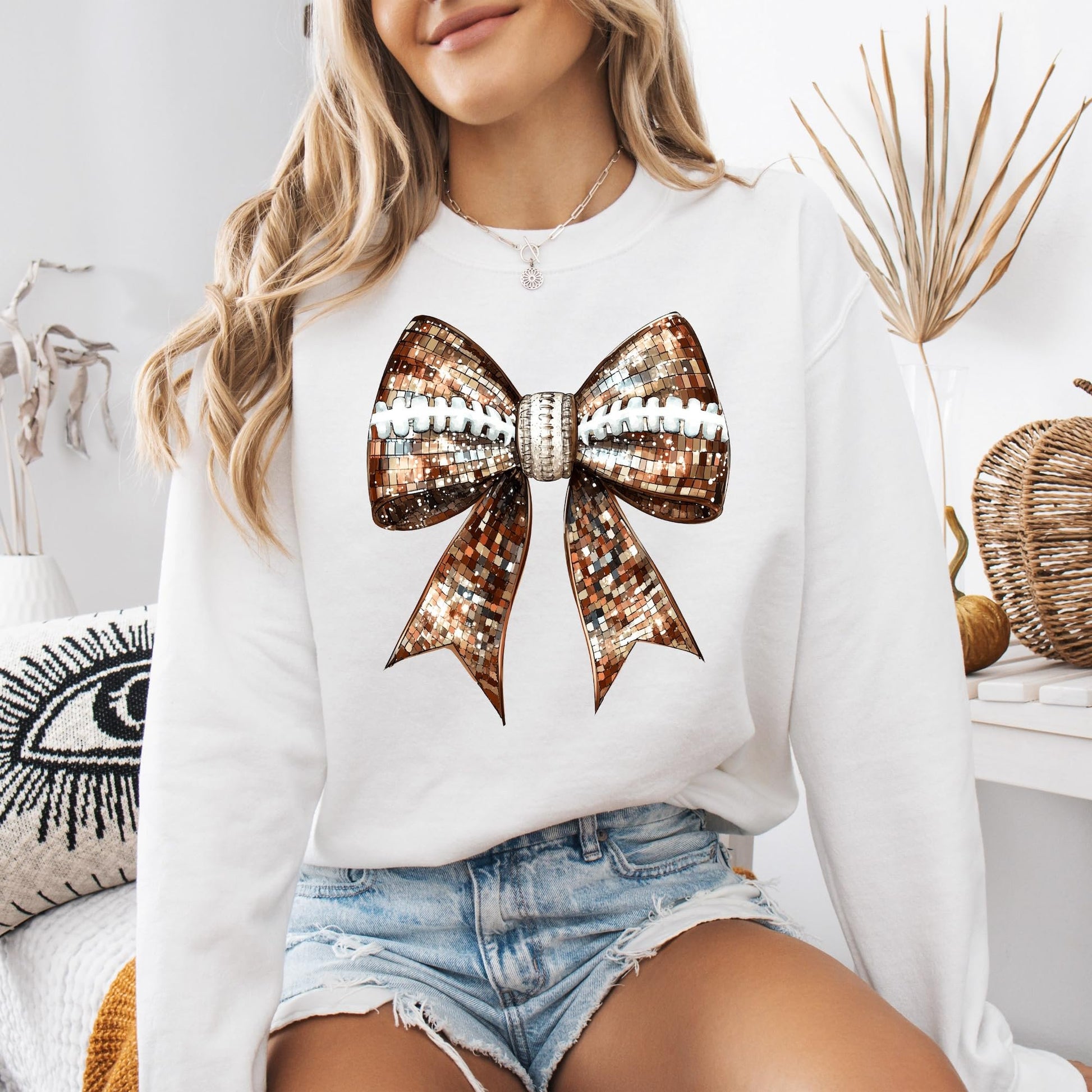 Flat lay of gray women's game day sweatshirt with disco football and ribbon bow graphic