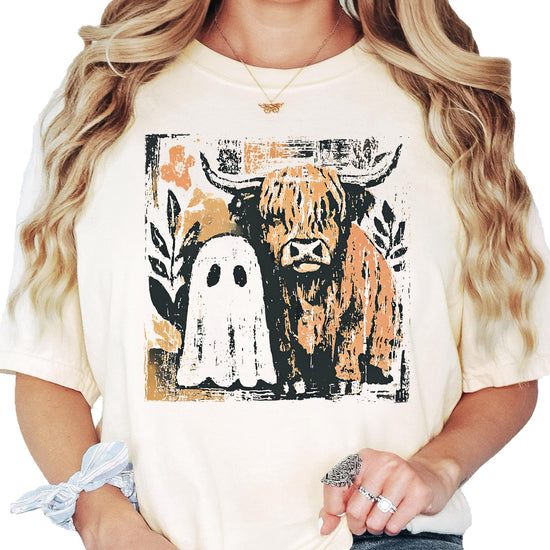 Women's ivory graphic tee featuring a cute ghost and highland cow Halloween design for fall
