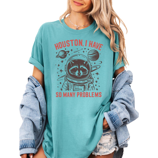 Seafoam green graphic tee featuring a cartoon raccoon in an astronaut suit with text Houston I Have So Many Problems