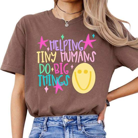 Woman wearing Helping Tiny Humans Do Big Things teacher tee showing relaxed unisex fit on garment-dyed Comfort Colors shirt