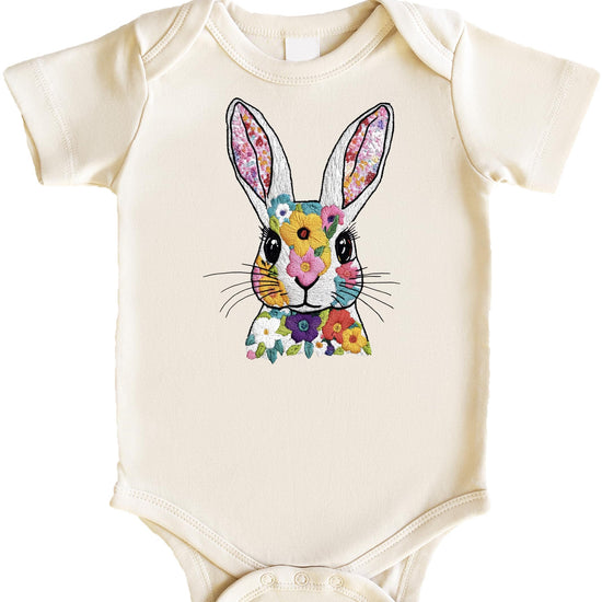 Baby girl wearing a peach snap bodysuit with a floral Easter bunny embroidery-style print
