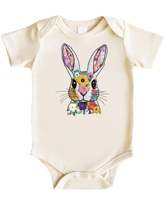 Baby girl wearing a peach snap bodysuit with a floral Easter bunny embroidery-style print