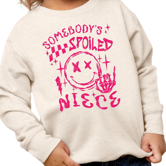 Front view of Somebody's Spoiled Niece kids sweatshirt in pink with bold alternative-style graphic print