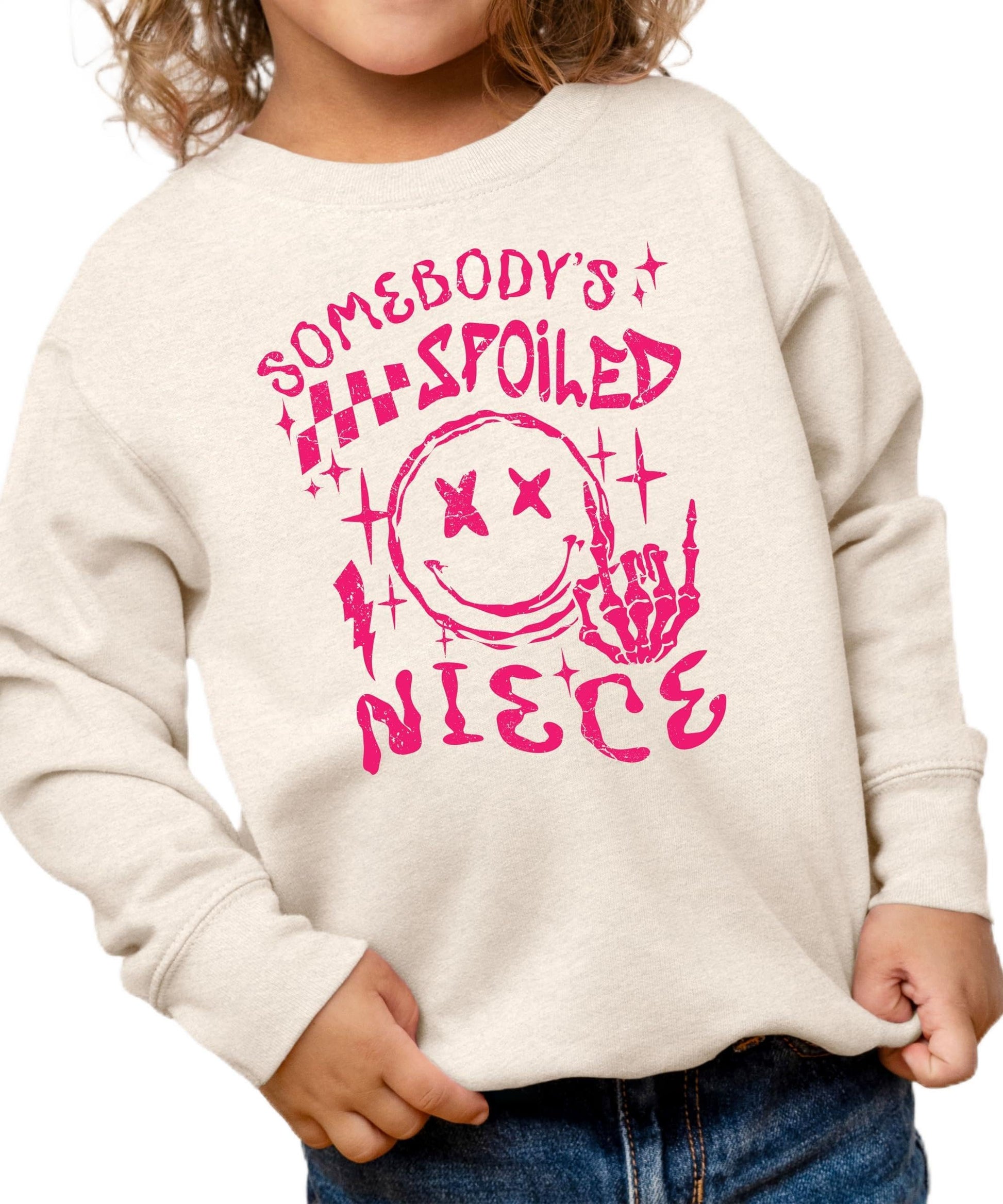 Front view of Somebody's Spoiled Niece kids sweatshirt in pink with bold alternative-style graphic print