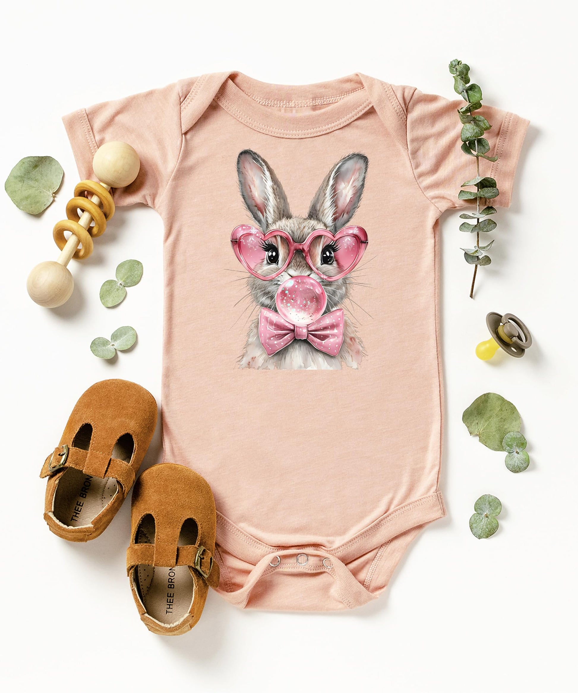 Detail shot of Easter rabbit with pink glasses and bow graphic on baby girl one-piece bodysuit
