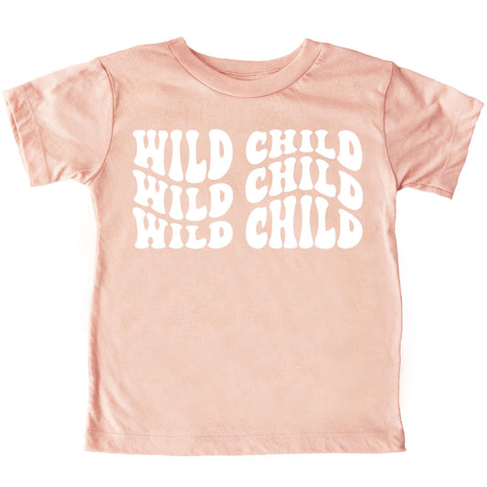 Close-up of Wild Child retro wavy lettering print on peach toddler shirt